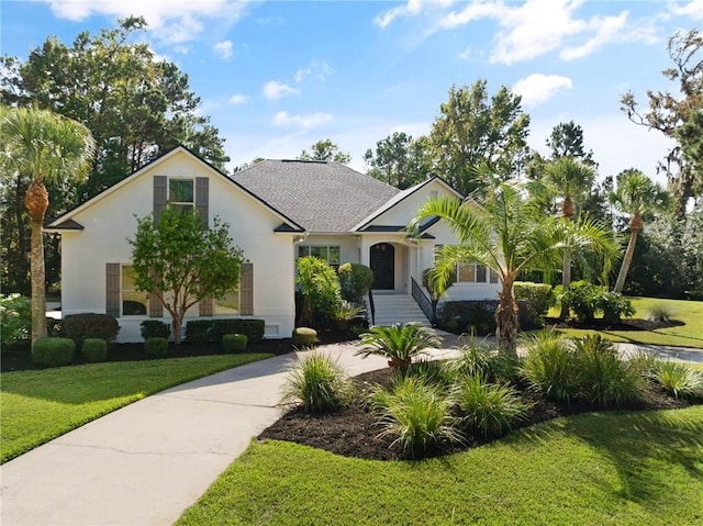 view of front of property featuring roof with shingles, a front yard, and stucco siding