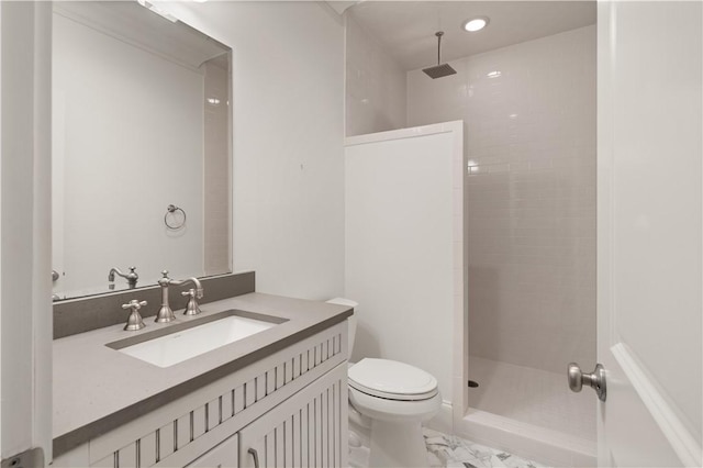 bathroom with vanity, toilet, and a tile shower