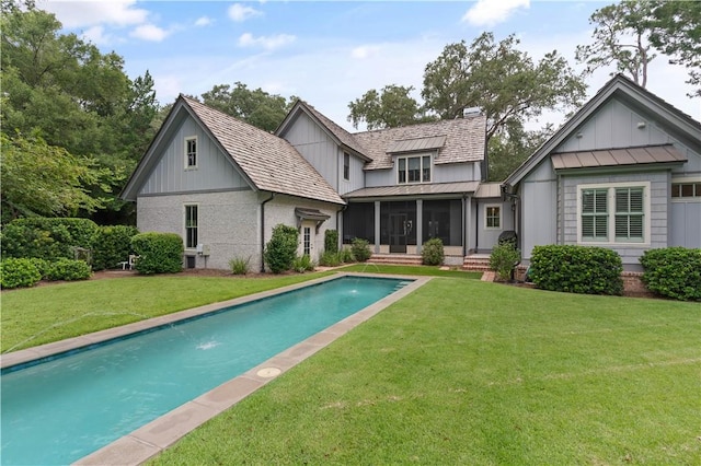 back of house with pool water feature, a lawn, and a sunroom