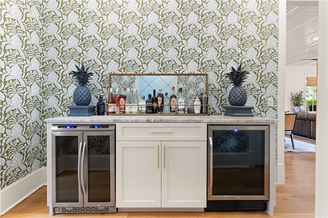 bar featuring white cabinets, light hardwood / wood-style floors, and beverage cooler