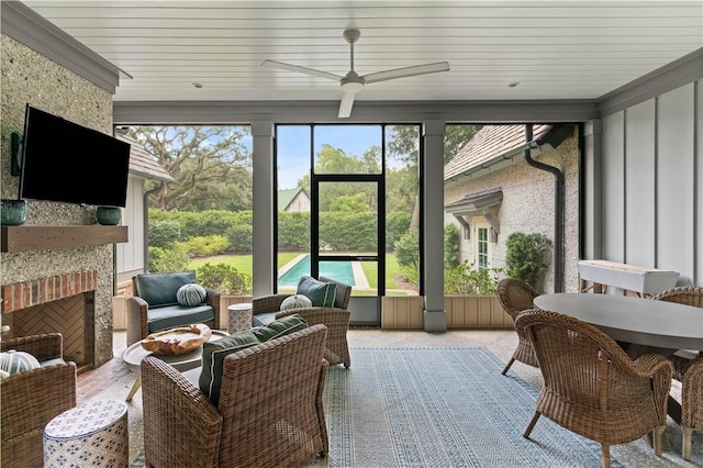 sunroom / solarium featuring a stone fireplace, ceiling fan, and wooden ceiling