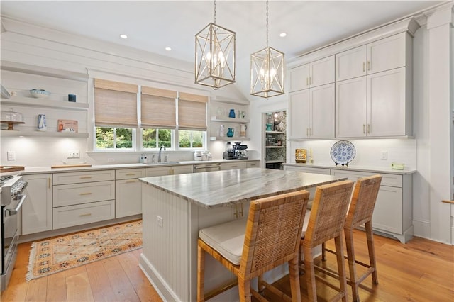 kitchen with light stone countertops, sink, a kitchen breakfast bar, a kitchen island, and light wood-type flooring