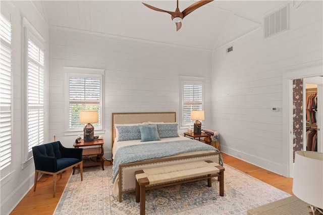 bedroom with a walk in closet, light wood-type flooring, ceiling fan, a closet, and lofted ceiling