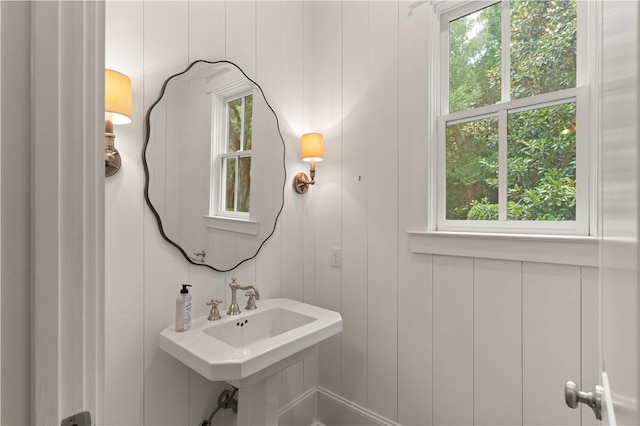 bathroom featuring sink, plenty of natural light, and wood walls