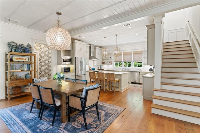 dining space featuring crown molding, light hardwood / wood-style flooring, wooden ceiling, and an inviting chandelier