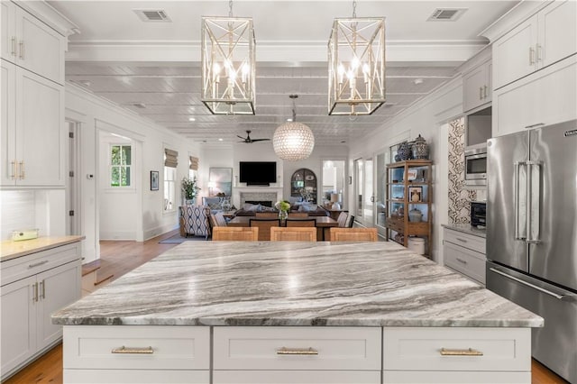 kitchen with a center island, stainless steel appliances, white cabinetry, and ceiling fan