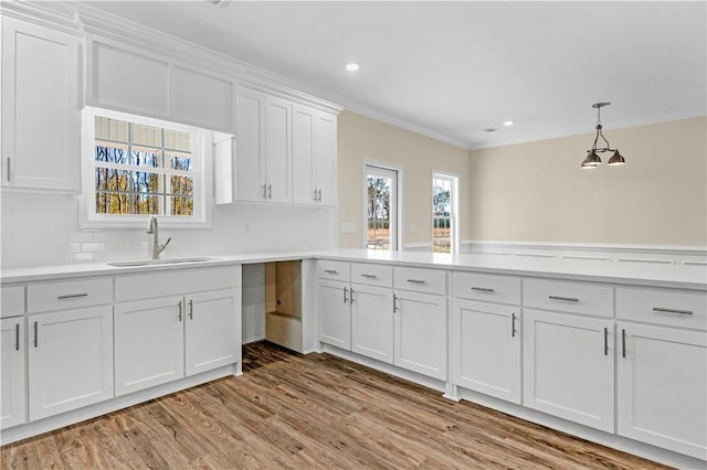 838 Old Ccc Rd, Brunswick, GA 31523 - kitchen featuring white cabinetry, sink, hanging light fixtures, light hardwood / wood-style flooring, and backsplash