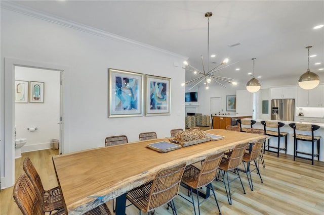 dining space featuring an inviting chandelier, light hardwood / wood-style floors, and ornamental molding