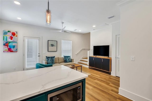 kitchen featuring ornamental molding, black microwave, ceiling fan, pendant lighting, and light hardwood / wood-style floors