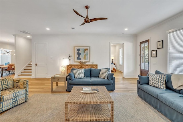 living room with ceiling fan, ornamental molding, and light wood-type flooring