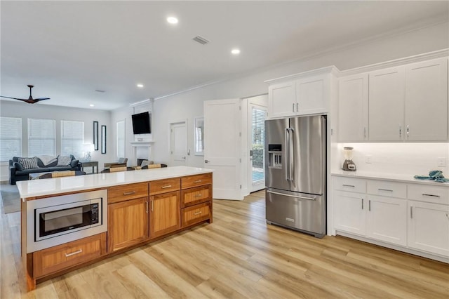 kitchen with appliances with stainless steel finishes, ceiling fan, crown molding, light hardwood / wood-style flooring, and white cabinetry