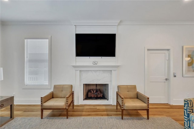 sitting room with a fireplace, wood-type flooring, and ornamental molding