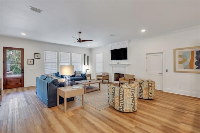 living room with light wood-type flooring, ceiling fan, and crown molding