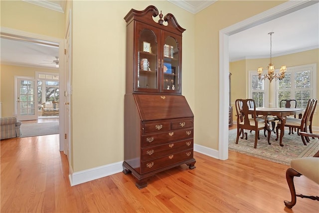 interior space featuring light wood finished floors, baseboards, ornamental molding, and ceiling fan with notable chandelier