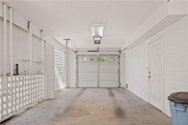 garage featuring concrete block wall and a garage door opener