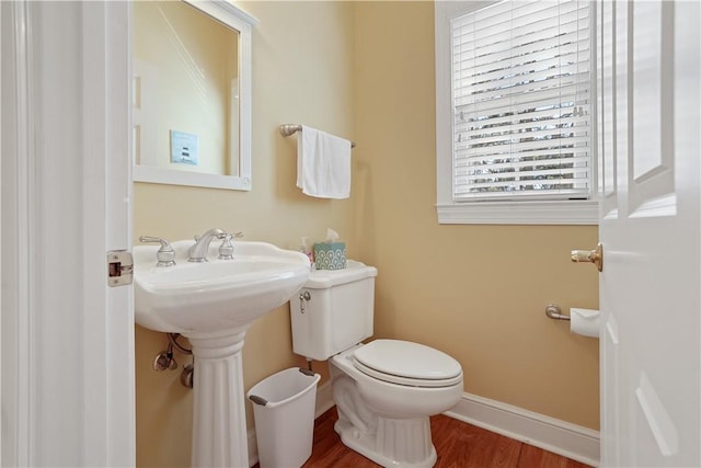 half bathroom featuring toilet, baseboards, and wood finished floors