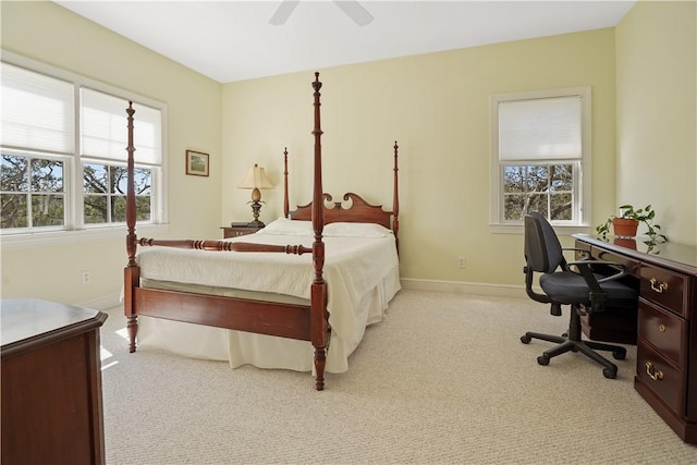 carpeted bedroom with a ceiling fan, multiple windows, and baseboards