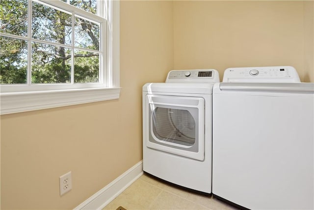 washroom with laundry area, light tile patterned flooring, washing machine and dryer, and baseboards