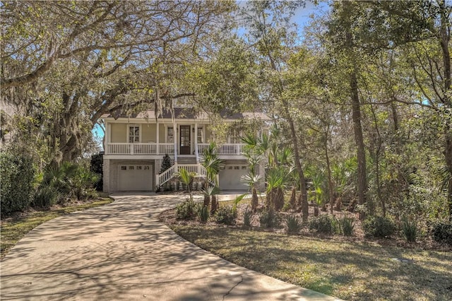 coastal inspired home with driveway, an attached garage, stairway, and a porch