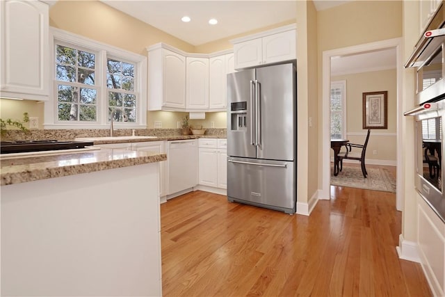 kitchen featuring light wood-type flooring, light stone countertops, white cabinetry, and stainless steel appliances