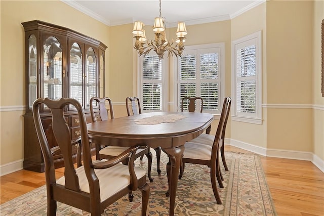 dining space with light wood-style floors, baseboards, crown molding, and an inviting chandelier