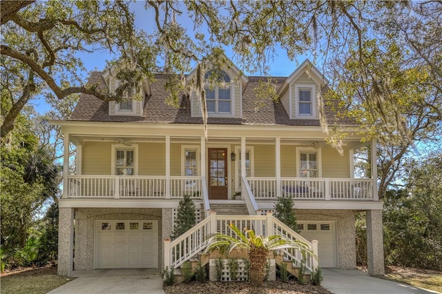 beach home featuring covered porch, concrete driveway, an attached garage, and stairs