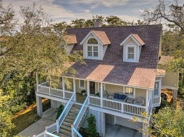 view of front of home with a chimney, a porch, stairway, and a shingled roof