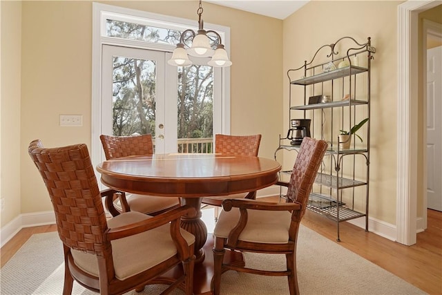 dining area with baseboards, an inviting chandelier, and wood finished floors