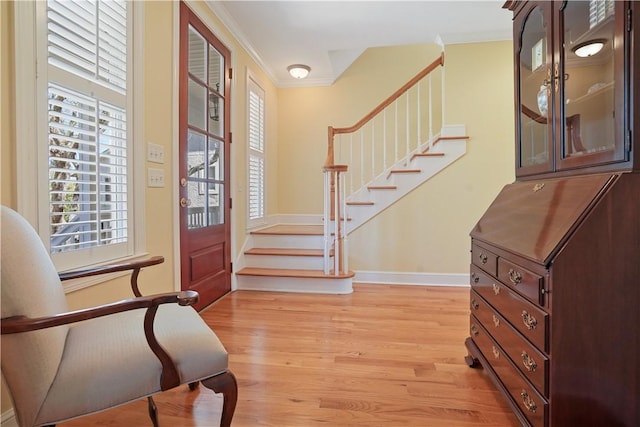 entrance foyer featuring light wood-type flooring, stairs, baseboards, and crown molding