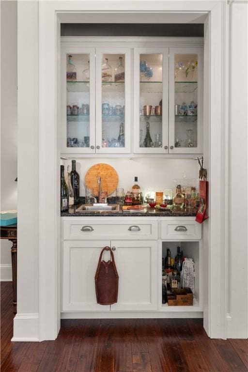 bar featuring dark hardwood / wood-style floors, white cabinetry, and sink