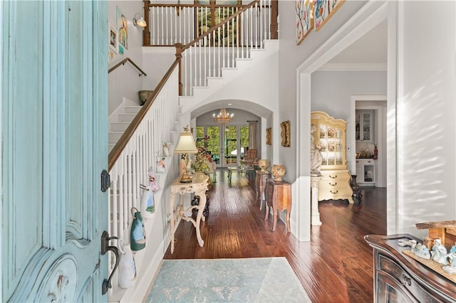 foyer with a chandelier, a towering ceiling, dark hardwood / wood-style flooring, and ornamental molding