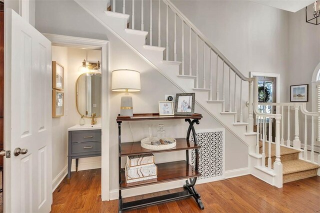 stairway featuring a high ceiling, baseboards, and wood finished floors