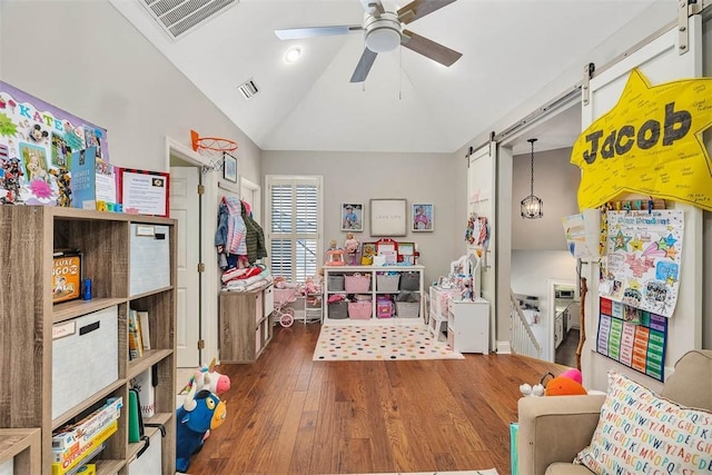 rec room with a ceiling fan, wood finished floors, visible vents, lofted ceiling, and a barn door