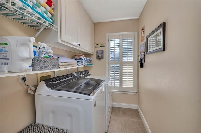 clothes washing area featuring washing machine and clothes dryer, plenty of natural light, cabinet space, and baseboards