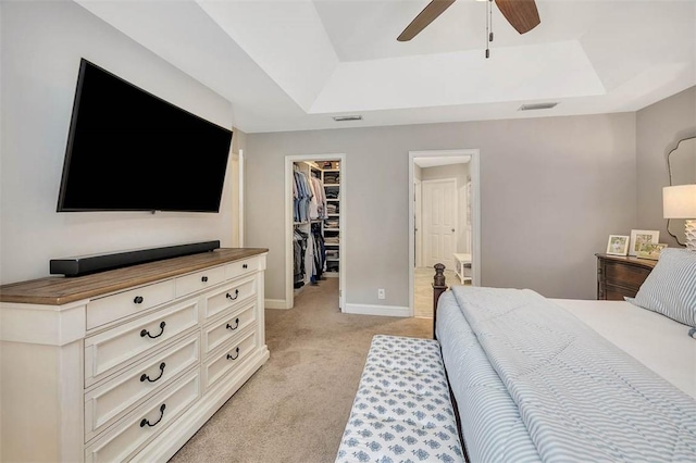 bedroom featuring a spacious closet, visible vents, light carpet, and a raised ceiling