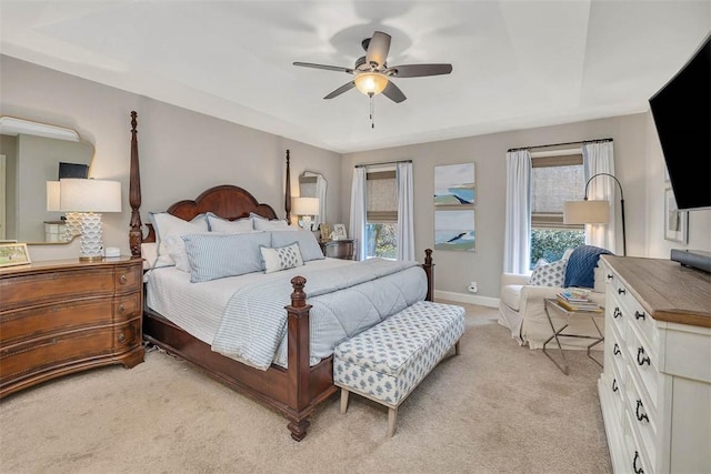 bedroom featuring baseboards, multiple windows, light colored carpet, and a ceiling fan