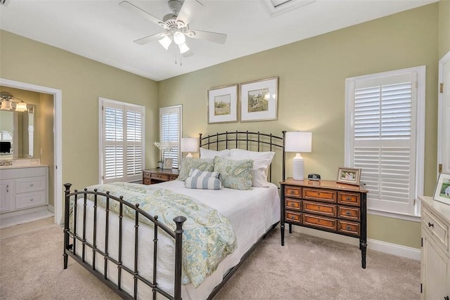 bedroom featuring light carpet, connected bathroom, a ceiling fan, and baseboards