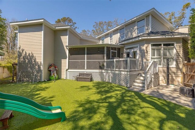 rear view of house with fence, a chimney, a lawn, and a sunroom