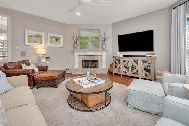 living room featuring ceiling fan, a fireplace with raised hearth, wood finished floors, and recessed lighting