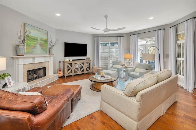 living area with ceiling fan, recessed lighting, wood finished floors, and a fireplace with raised hearth