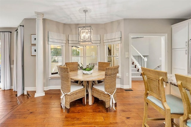 dining space featuring a notable chandelier, light wood-style floors, and ornate columns