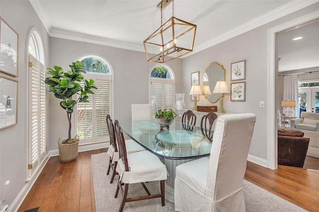 dining space featuring baseboards, crown molding, and hardwood / wood-style flooring