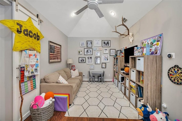 living room with a ceiling fan, visible vents, baseboards, lofted ceiling, and a barn door