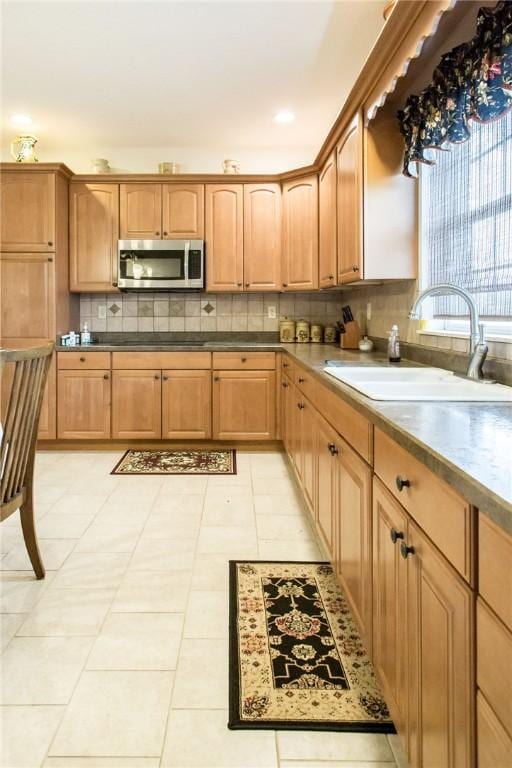 5604 Woodstone Dr, Blackshear, GA 31516 - kitchen featuring stainless steel microwave, light tile patterned flooring, black electric cooktop, decorative backsplash, and a sink