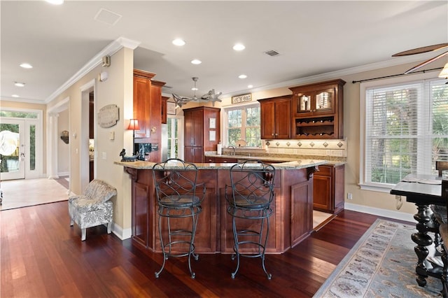 kitchen featuring kitchen peninsula, a healthy amount of sunlight, and dark hardwood / wood-style floors