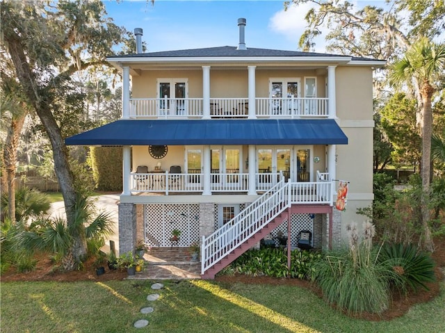 view of front of house with covered porch, a balcony, and a front yard