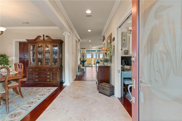 hall with hardwood / wood-style floors, decorative columns, and ornamental molding