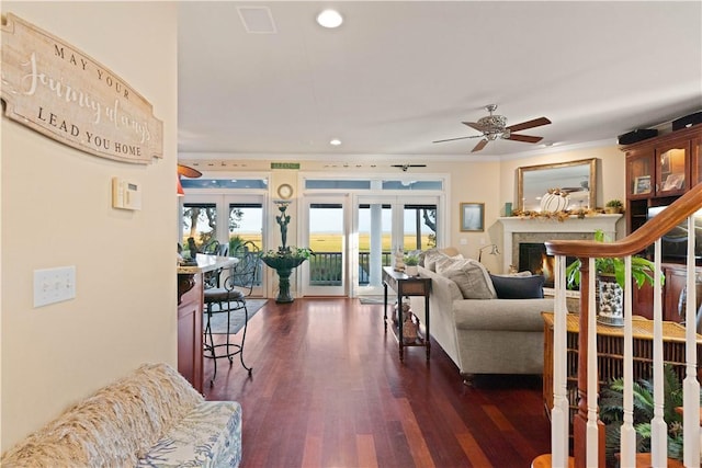 living room featuring dark wood-type flooring, french doors, crown molding, ceiling fan, and a premium fireplace