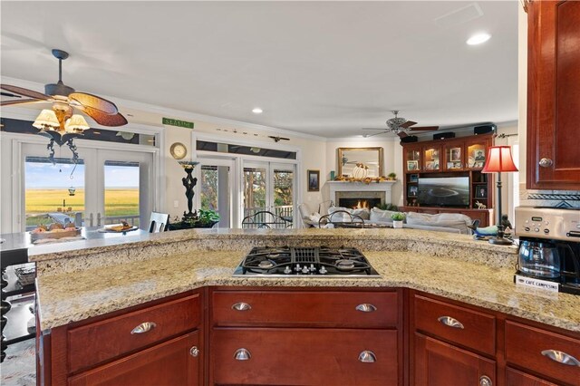 kitchen with light stone counters, ornamental molding, stainless steel gas cooktop, and french doors