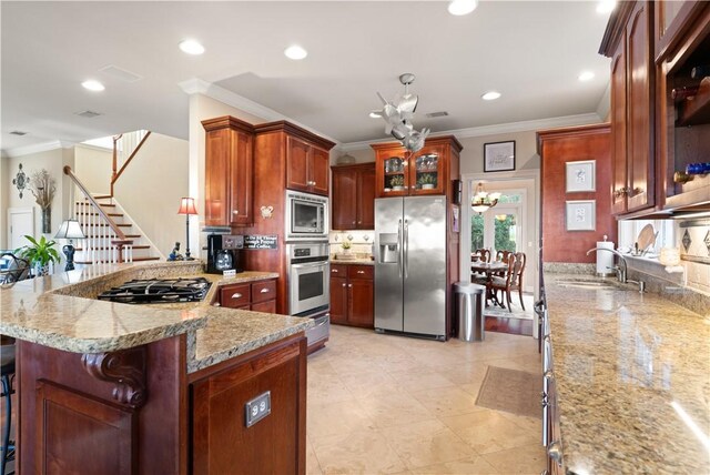 kitchen with appliances with stainless steel finishes, ornamental molding, a kitchen breakfast bar, and sink